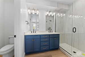 Bathroom featuring double vanity, a shower stall, and light wood-type flooring