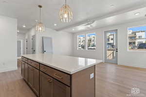 Kitchen with a kitchen island, decorative light fixtures, recessed lighting, light wood-style flooring, and dark brown cabinets