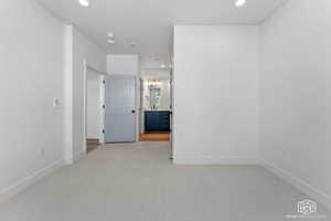 Empty room with light carpet and recessed lighting