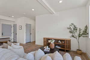 Living area with wood finished floors, beamed ceiling, and recessed lighting