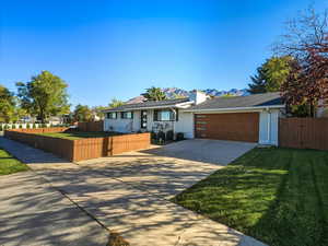 Ranch-style home featuring a fenced front yard, driveway, brick siding, a gate, and a mountain view