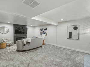 Carpeted living room with recessed lighting, a glass covered fireplace, and a textured ceiling