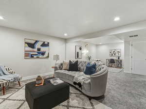 Carpeted living area with a textured ceiling and recessed lighting