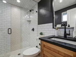 Full bathroom with vanity, a shower stall, backsplash, tile walls, and a textured ceiling