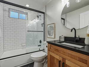 Bathroom featuring vanity, combined bath / shower with glass door, tile patterned floors, and a textured ceiling