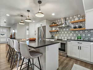 Kitchen featuring open shelves, a breakfast bar area, white cabinetry, dark wood-style floors, and stainless steel appliances