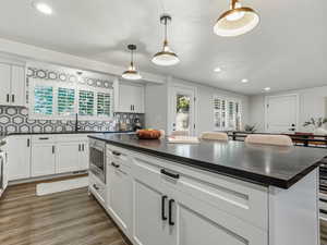 Kitchen with recessed lighting, white cabinets, decorative light fixtures, a textured ceiling, and tasteful backsplash
