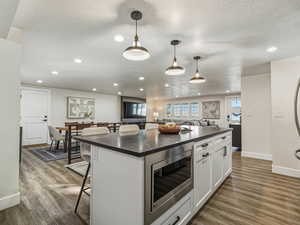 Kitchen with a kitchen breakfast bar, open floor plan, stainless steel microwave, a center island, and white cabinets