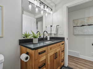 Half bathroom featuring vanity and wood finished floors
