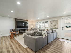 Living area with light wood-style flooring, recessed lighting, a tiled fireplace, and a textured ceiling