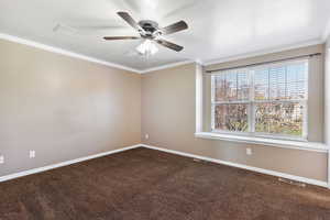 Empty room featuring ornamental molding, dark carpet, a textured ceiling, and ceiling fan