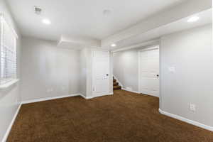 Below grade area featuring dark colored carpet, recessed lighting, and stairway