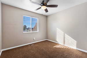 Spare room featuring carpet and ceiling fan