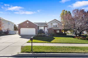 Tri-level home featuring driveway, brick siding, and a garage