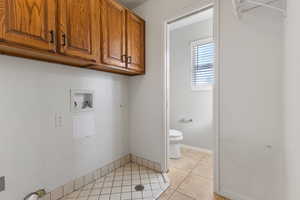 Laundry room featuring washer hookup, light tile patterned floors, and cabinet space