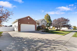 View of side of property with driveway, a gate, brick siding, and a garage