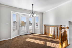 Unfurnished dining area featuring carpet, ornamental molding, and a chandelier