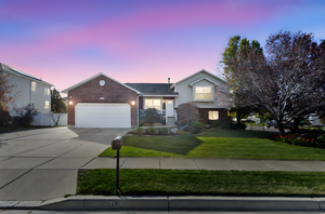 View of front of property featuring concrete driveway, brick siding, and an attached garage