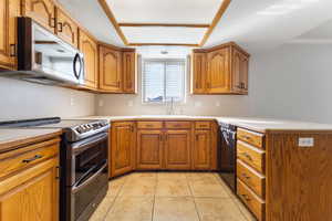 Kitchen featuring appliances with stainless steel finishes, light countertops, and brown cabinets