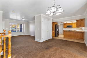 Kitchen featuring open floor plan, a peninsula, light colored carpet, pendant lighting, and brown cabinets