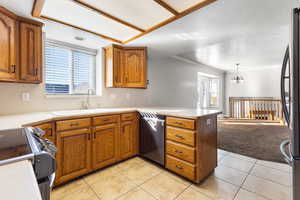 Kitchen with light countertops, brown cabinets, healthy amount of natural light, appliances with stainless steel finishes, and ornamental molding