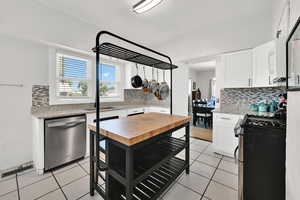 Kitchen with light stone counters, stainless steel appliances, light tile patterned floors, and decorative backsplash