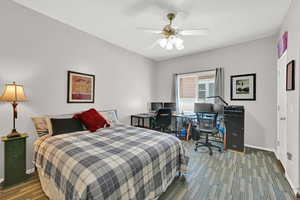 Bedroom featuring dark carpet, a ceiling fan, and an office area