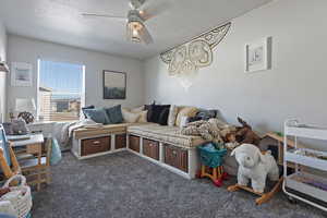 Carpeted living area featuring a textured ceiling and ceiling fan