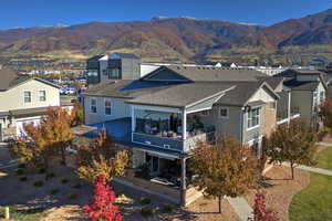 Back of house featuring a residential view, a mountain view, roof with shingles, and a balcony
