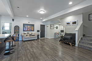 Living area with recessed lighting, dark wood-type flooring, stairway, a textured ceiling, and beamed ceiling