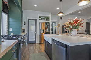 Kitchen with appliances with stainless steel finishes, light stone counters, hanging light fixtures, dark wood-type flooring, and recessed lighting
