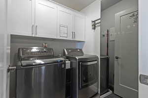 Washroom with separate washer and dryer, cabinet space, dark wood-style floors, and a textured ceiling