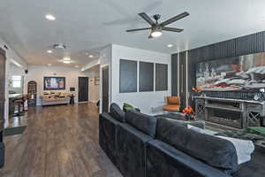 Living room featuring a lit fireplace, a textured ceiling, wood-type flooring, recessed lighting, and ceiling fan