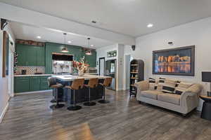 Kitchen featuring green cabinetry, light countertops, a kitchen island, a breakfast bar, and backsplash