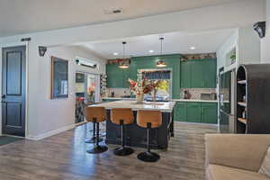 Kitchen with backsplash, dark wood-type flooring, a center island, green cabinetry, and recessed lighting