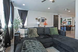 Living area with wood finished floors, a textured ceiling, recessed lighting, and ceiling fan