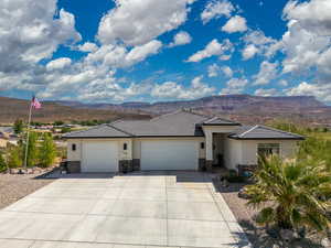 Prairie-style house with stone siding, an attached garage, stucco siding, and a mountain view