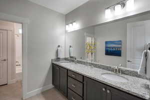 Bathroom featuring double vanity, light tile patterned flooring, and tub / shower combination