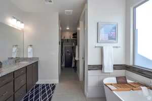 Bathroom featuring vanity, a soaking tub, light tile patterned floors, and a walk in closet