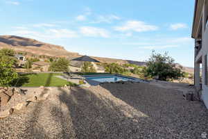 View of green lawn featuring a patio, an outdoor pool, and a mountain view