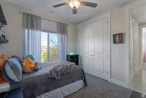 Tiled bedroom with carpet flooring, a closet, and a ceiling fan