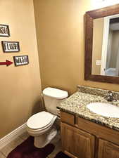 Half bathroom featuring dark tile patterned floors and vanity