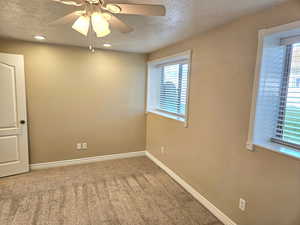 Spare room featuring a textured ceiling, carpet floors, and a ceiling fan