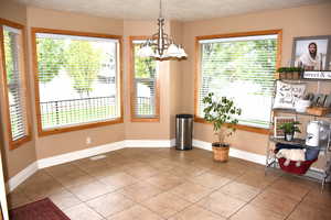 Unfurnished dining area with tile patterned floors, a chandelier, and a textured ceiling