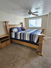 Carpeted bedroom with a textured ceiling and a ceiling fan