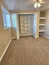 Unfurnished bedroom featuring carpet, a textured ceiling, a closet, and ceiling fan