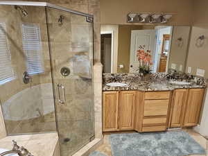 Full bathroom with double vanity, a shower stall, and light tile patterned floors