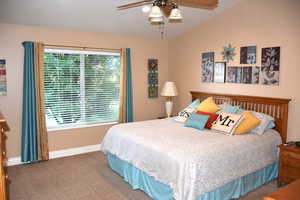Bedroom with carpet flooring, ceiling fan, and vaulted ceiling