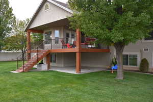 Rear view of house with a patio area, stucco siding, a yard, and stairs