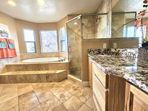 Full bath featuring a textured ceiling, a bath, a stall shower, and vanity